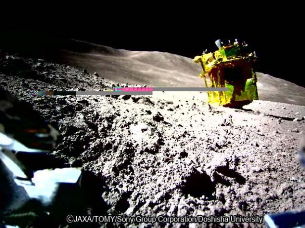 Der SLIM-Lander der japanischen Raumfahrtagentur JAXA steht auf der staubigen Mondoberfläche, im Vordergrund ist ein Teil des Mini-Rovers SORA-Q zu sehen.