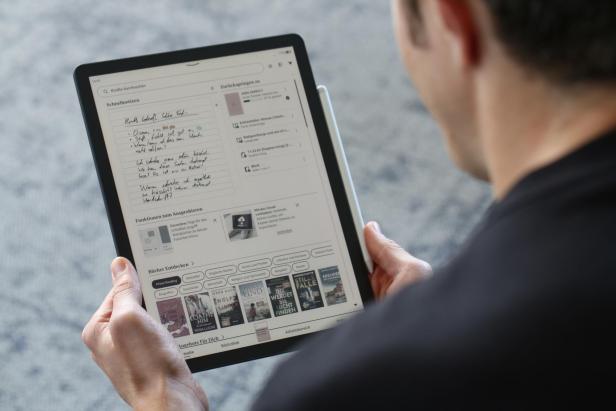 Person hält einen Kindle Scribe mit handschriftlichen Notizen und E-Book-Auswahl auf dem Display.