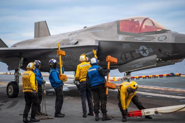 Bodenpersonal bereitet einen F-35-Kampfjet auf einem Flugzeugträger für den Einsatz vor.