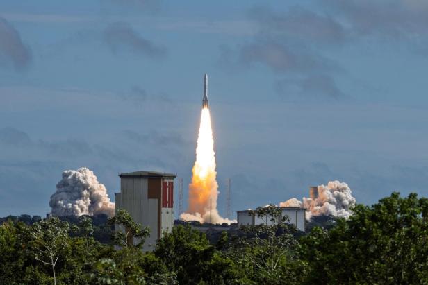 Eine Rakete startet vor einem bewaldeten Hintergrund in den Himmel und hinterlässt eine große Rauchwolke.