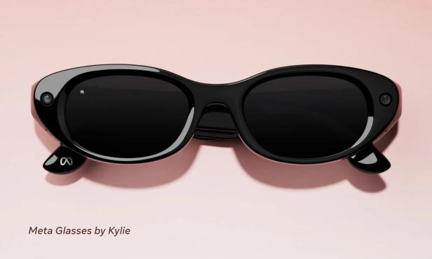 Schwarze, schmale Cat-Eye-Smartglasses von Meta mit der Aufschrift „Meta Glasses by Kylie“ auf rosafarbenem Hintergrund.