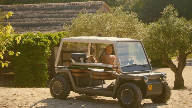 Ein E-Buggy steht vor kleinen Bäumen auf sandigem Boden