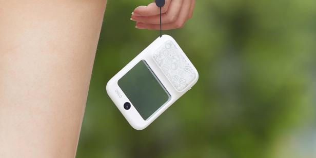Frau trägt Mini-Kamera in einer Hand