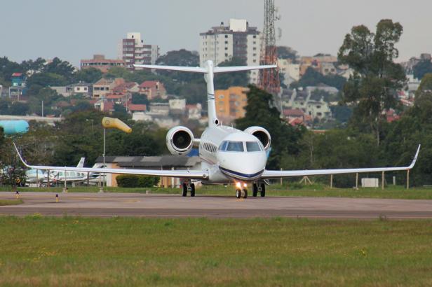 Weißer Businessjet rollt auf einer Startbahn.
