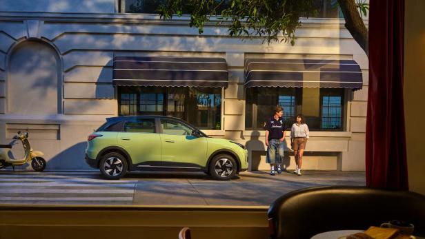 grünes Geely E2 vor mediterran wirkender Stadtkulisse