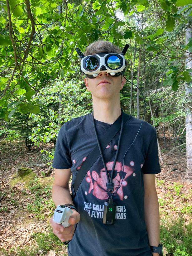 Person mit VR-Brille und Controller im Wald.