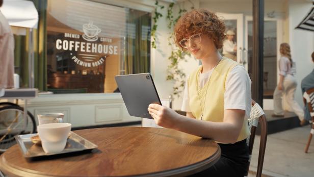 Person sitzt im Café und nutzt ein Tablet.