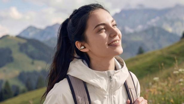 Eine Frau wandert in den Bergen und trägt kabellose Clip-Kopfhörer.
