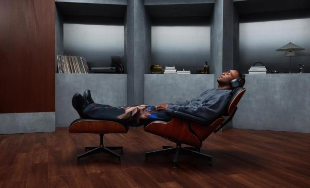 Mann mit Kopfhörern lehnt entspannt in einem Designer-Loungesessel.