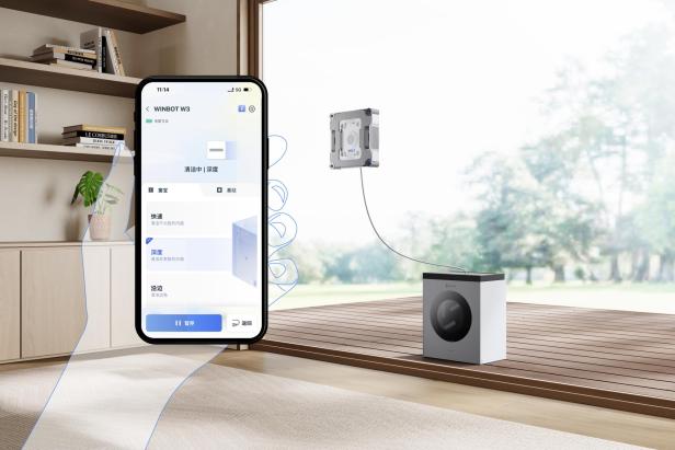 Ein Smartphone steuert per App den ECOVACS Winbot W3 Omni, der eine Fensterscheibe reinigt und mit einer Basisstation verbunden ist.