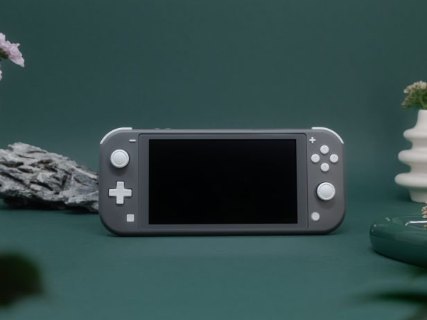 Eine graue Nintendo Switch Lite steht vor einem dunkelgrünen Hintergrund, flankiert von einem Stein und einer kleinen Vase.