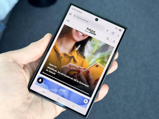 Eine Hand hält ein aufgeklapptes Falt-Smartphone mit geöffneter Website.