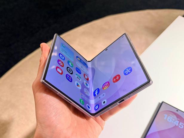 Aufgeklapptes Fold-Smartphone in der Hand mit Apps auf dem Display.