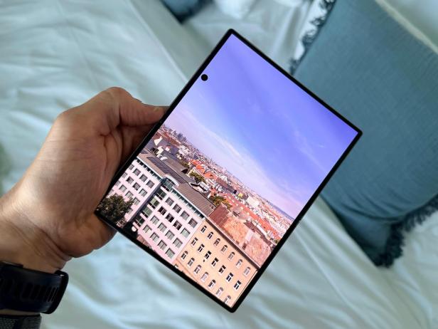 Hand hält ein aufgeklapptes Falt-Smartphone mit Stadtbild auf dem Display.
