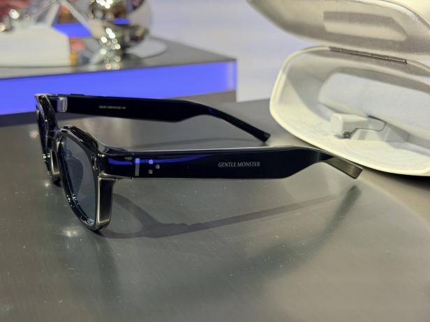 Smarte schwarze Brille mit transparenten Bügeln neben Etui.