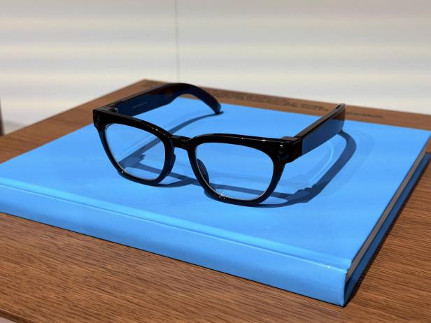 Samsung-Prototyp einer schwarzen KI-Brille mit breiten Bügeln und integrierten Kameras auf einer blauen Präsentationsfläche.
