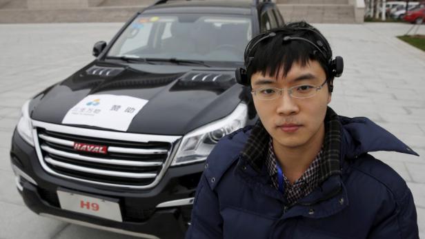 Forscher Zhang Zhao mit dem Hirnsignal-Messgerät vor dem Versuchsfahrzeug in Tianjin