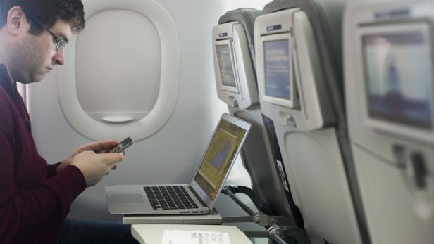 A man uses his mobile phone and laptop to test a new high speed inflight Internet service named Fli-Fi while on a special JetBlue media flight out of John F. Kennedy International Airport in New York December 11, 2013. Wi-Fi in the sky is taking off, promising much better connections for travelers and a bonanza for the companies that sell the systems. With satellite-based Wi-Fi, Internet speeds on jetliners are getting lightning fast. And airlines are finding that travelers expect connections in the air to rival those on the ground - and at lower cost. Picture taken December 11, 2013. To match Analysis AIRLINES-WIFI/ REUTERS/Lucas Jackson (UNITED STATES - Tags: TRANSPORT BUSINESS SCIENCE TECHNOLOGY TELECOMS TRAVEL)