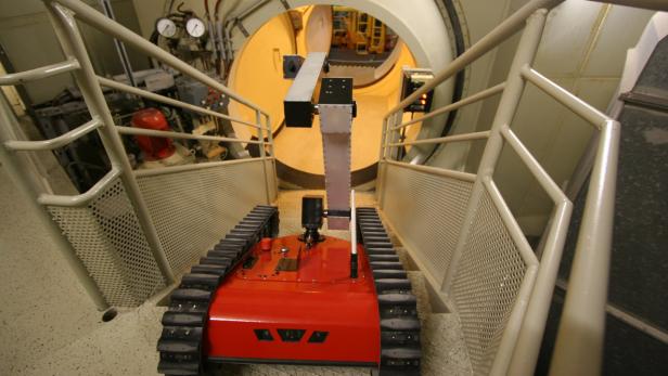 Ein roter Roboter mit Raupenketten fährt eine Treppe in einem Tunnel hinunter.