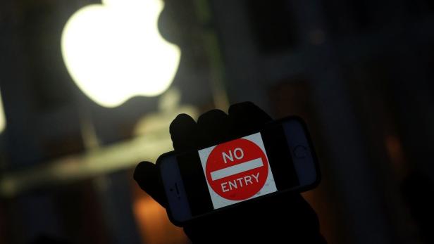 Demonstrant mit einem &quot;No Entry&quot;-Schriftzug auf seinem iPhone vor einem Apple Store