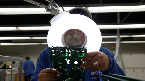 An employee inspects a printed circuit board at the assembly line of a factory that exports to the U.S. in Ciudad Juarez