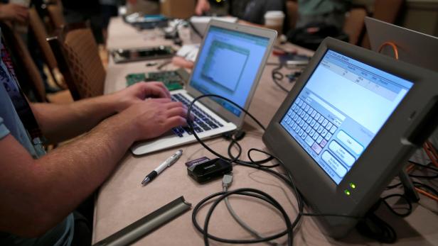 A hacker tries to access and alter data from an electronic poll book in a Voting Machine Hacking Village during the Def Con hacker convention in Las Vegas