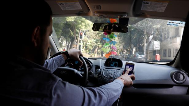 Uber driver checks the route on a mobile phone inside his car in Mexico City