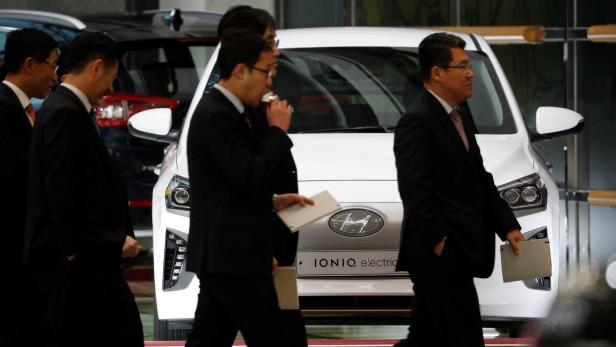 Employees of Hyundai Motor walk past a Hyundai Motor's hybrid car IONIQ after the company's New Year ceremony in Seoul
