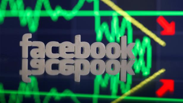 A 3D-printed Facebook logo is seen in front of displayed stock graph