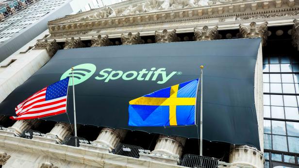 The Spotify logo hangs on the facade of the New York Stock Exchange with U.S. and Swedish flags as the company lists its stock with a direct listing in New York