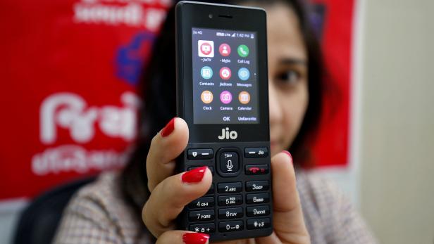 A sales person displays JioPhone as she poses for a photograph at a store of Reliance Industries' Jio telecoms unit, on the outskirts of Ahmedabad