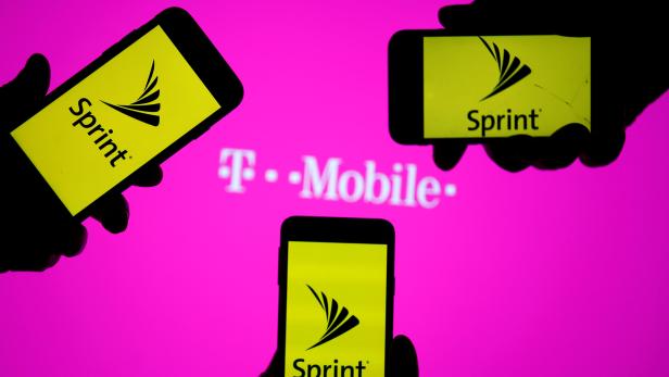 A smartphones with Sprint logo are seen in front of a screen projection of T-mobile logo, in this picture illustration