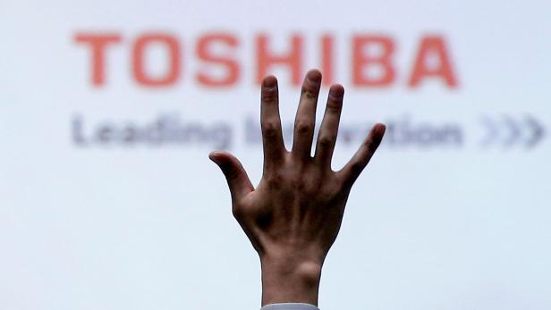 FILE PHOTO: FILE PHOTO: A reporter raises his hand for a question during a news conference at the Toshiba Corp company headquarters in Tokyo, Japan