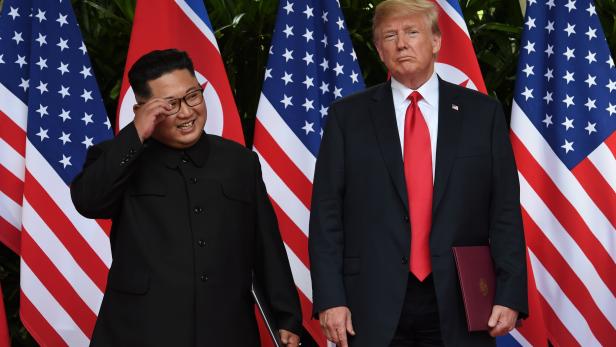 U.S. President Donald Trump and North Korea's leader Kim Jong Un react during their summit at the Capella Hotel on Sentosa island in Singapore