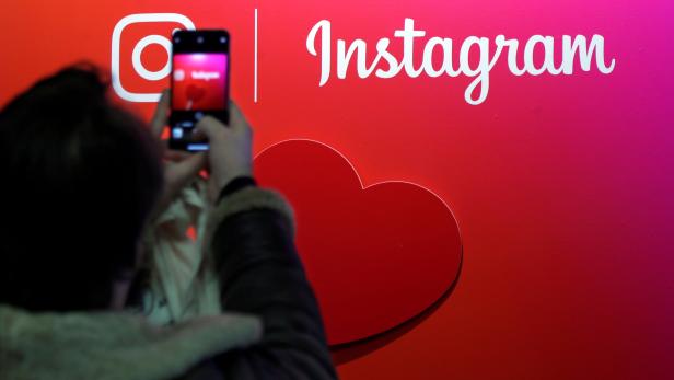 FILE PHOTO: A visitor takes a picture of the Instagram application logo at the Young Entrepreneurs fair in Paris