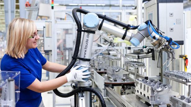 VW-Mitarbeiterin mit einem kollaborativen Roboter