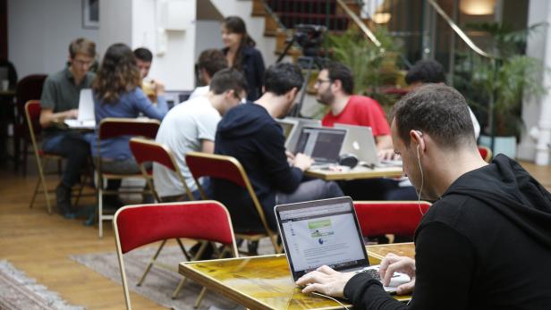 Entrepreneurs work at their computer laptops at the so-called "incubator" of French high-tech start-ups "TheFamily" in Paris