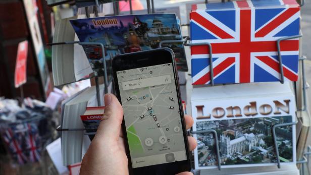A photo illustration shows the Uber app and London themed postcards in London