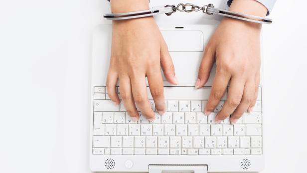 Female hands handcuffed to white keyboard