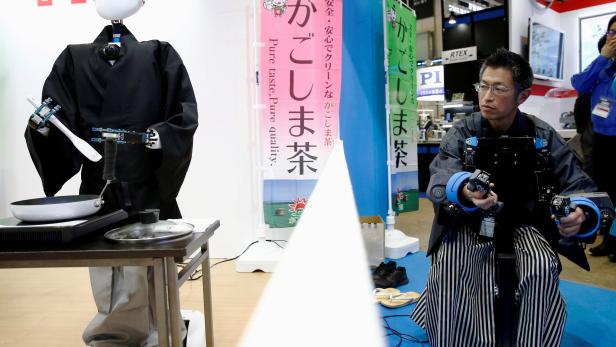 A tea master operates SEED Solutions' platform robot SEED-Noid by remote control as it roasts tea leaves during its demonstration at Robot Development & Application Expo in Tokyo