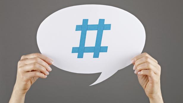 Two hands holding up white speech bubble with hashtag