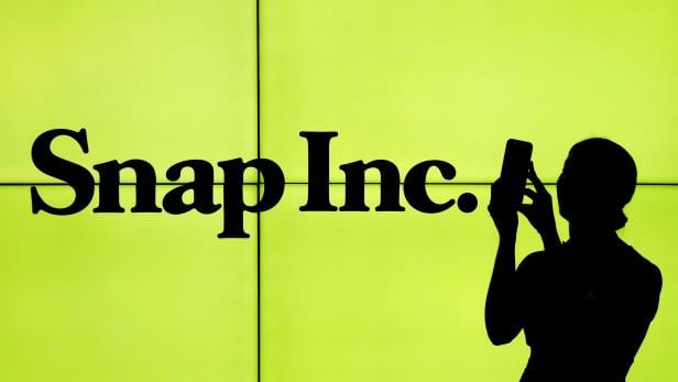 FILE PHOTO - A woman stands in front of the logo of Snap Inc. on the floor of the New York Stock Exchange in New York City