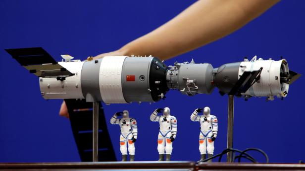 FILE PHOTO: A model of the Tiangong-1 space lab module, the Shenzhou-9 manned spacecraft and three Chinese astronauts is displayed during a news conference