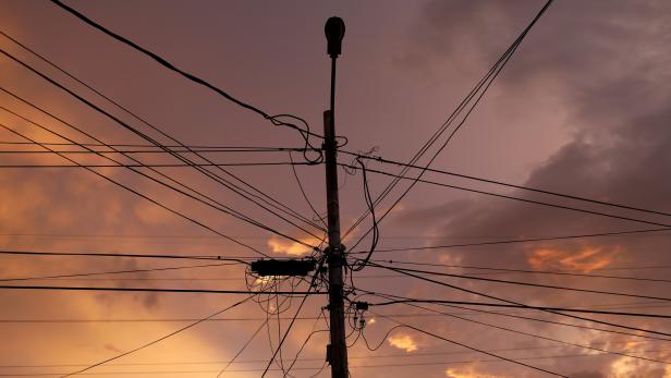 A street light post and power lines are seen at sunset during a blackout in Maracaibo