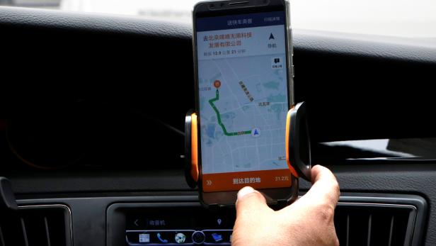 A Didi Chuxing driver checks the information on the application in his car in Beijing