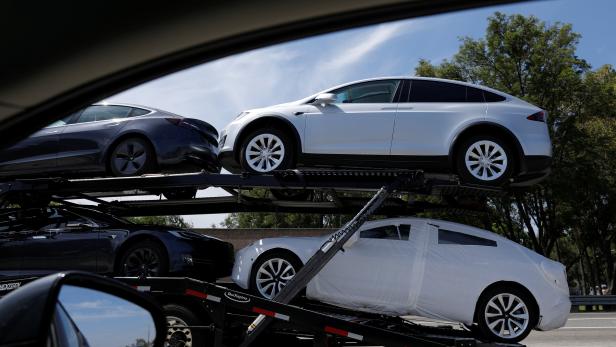 Newly manufactured Tesla vehicles are  transported along a freeway in Los Angeles, California