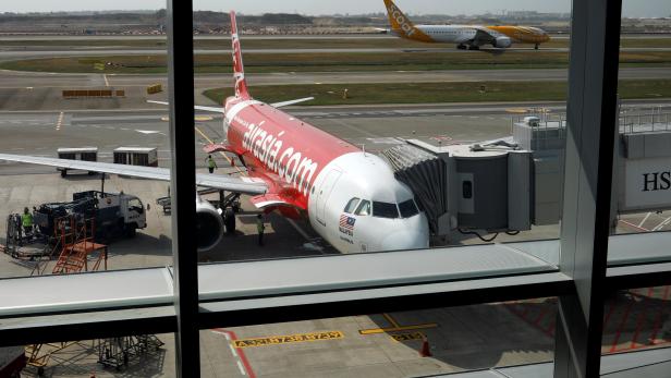 A Scoot airplane takes off past an Airasia airplane at Changi Airport Terminal 4 in Singapore