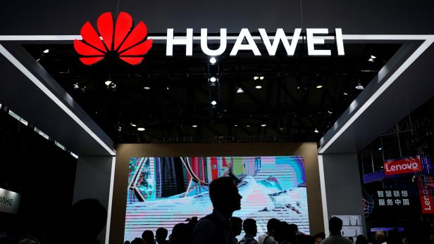 People walk past a sign board of Huawei at CES (Consumer Electronics Show) Asia 2018 in Shanghai