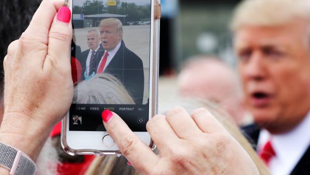 Woman shoots a mobile phone picture of U.S. President Trump as he arrives for an evening campaign rally in Cincinnati, Ohio