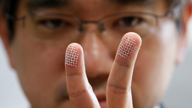 Echizen, a professor at Japan's National Institute of Informatics, poses to a photographer as he gestures with his fingers covered with a home-made biometric jammer during a demonstration of his experiment for Reuters in Tokyo